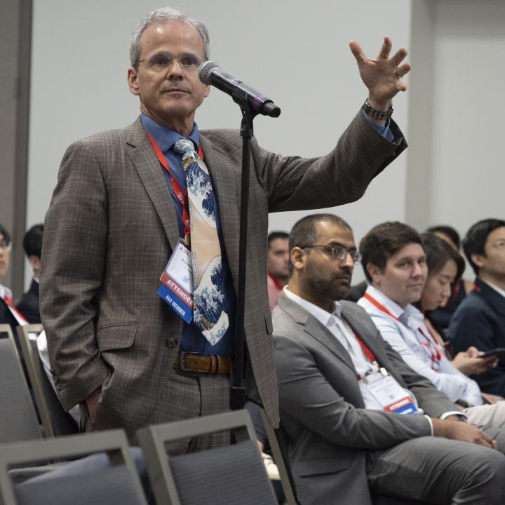 Researcher at conference standing at microphone asking a question