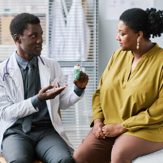 African American physician showing medications to heavy set African American woman patient