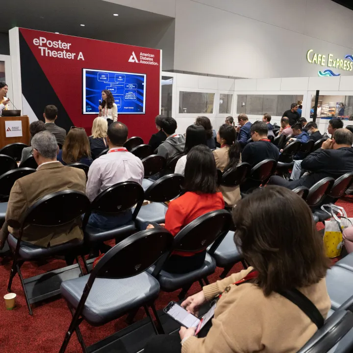 People seated in auditorium watching research presentation