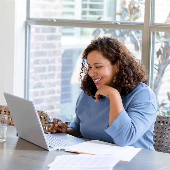 Woman smiling studying and looking at laptop