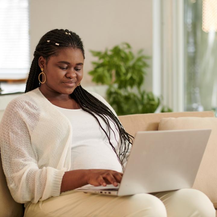 African American woman on couch working on laptop computer