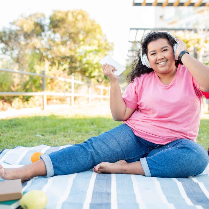 Happy young lady listening to headphones outside