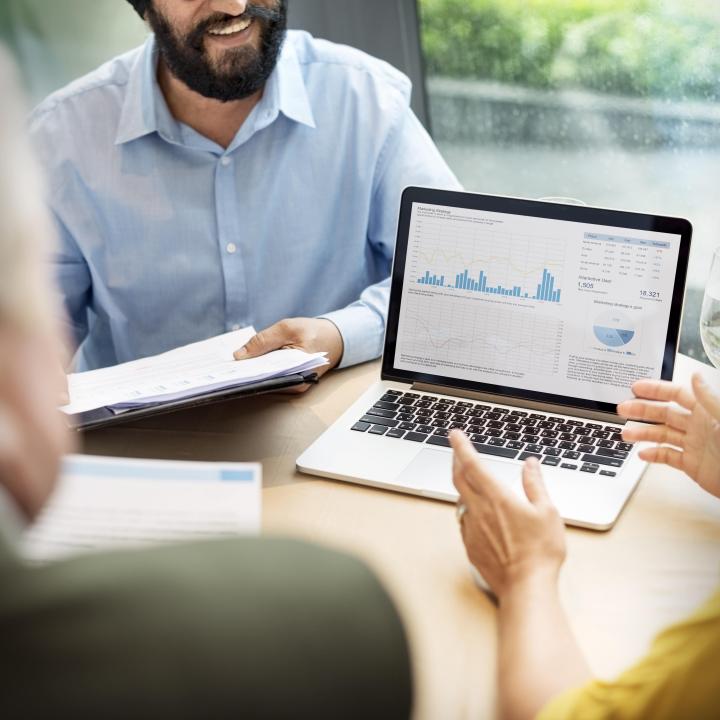 People at table looking at laptop showing data analytics