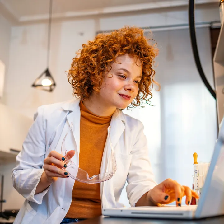 young woman working in a medical lab. Close up of scientist woman working in laboratory with laptop.