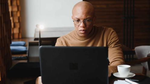 African American man in cafe looking at laptop computer