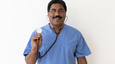 Smiling Indian physician holding up stethoscope