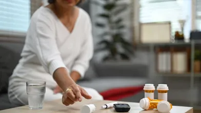 Woman reaching for medication on table