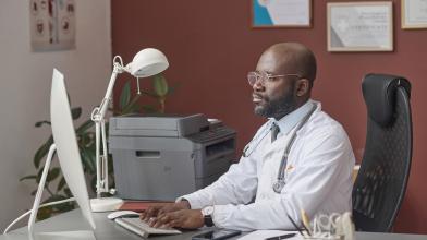 African American physician working at desk on computer