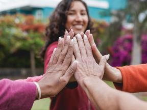 Smiling woman putting hands together with others