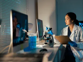 Female Asian medical researcher looking at desktop computer screen