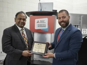 Two smiling men at ADA Scientific Sessions, one presents a framed award to the other.