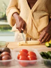 African American woman cutting up banana on cutting board