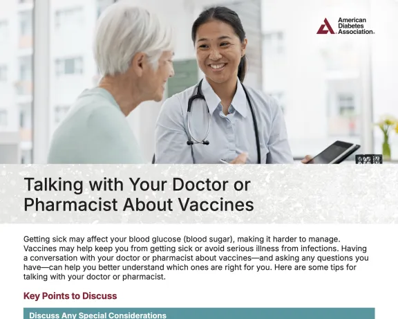Smiling doctor talks with an older patient in a clinic setting.