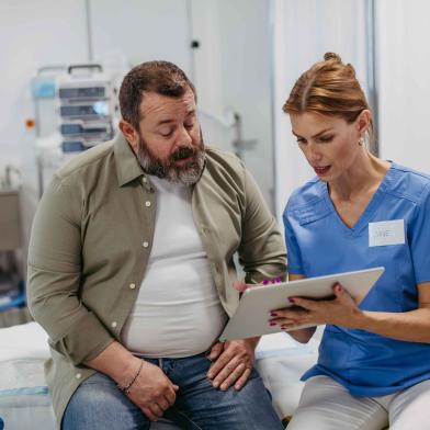 Heavy man talking to female doctor before surgery