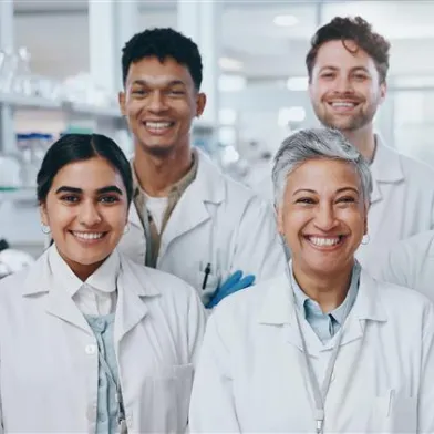 A group of diabetes researchers pose together and smile in a lab