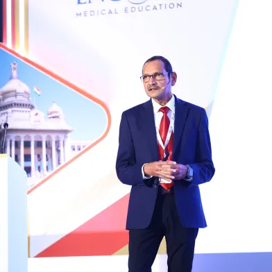 Man in suit speaks at ADA conference; ADA logo, '85' on podium; 'Medical Education' on screen.