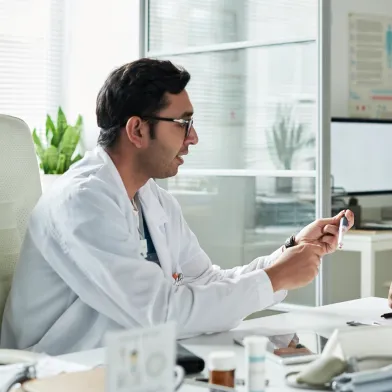 Doctor consults patient at desk with "DIABETES" poster.