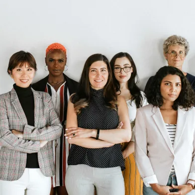 Diverse group of seven women standing confidently, some smiling.
