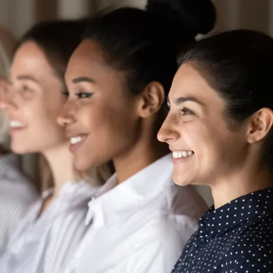 Four diverse women smiling, looking right.