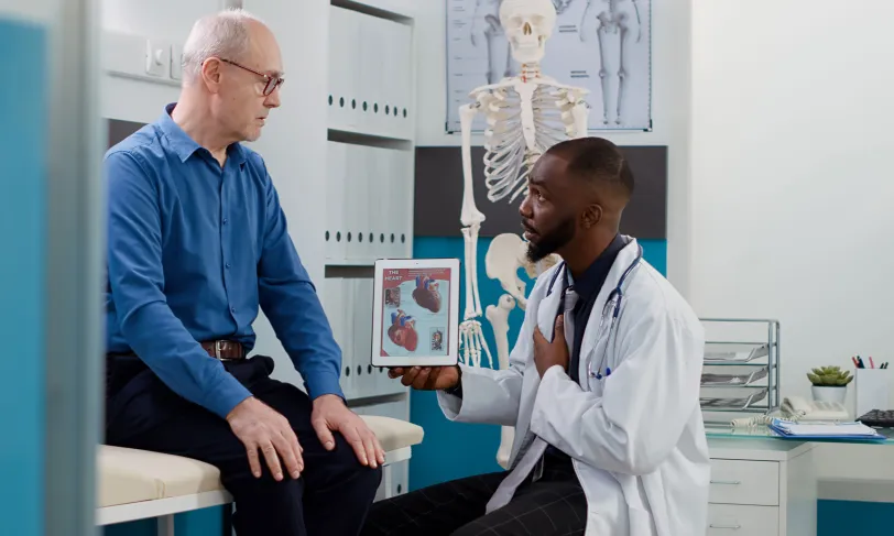 Senior cardiac patient talking to cardiologist using heart graphics on tablet