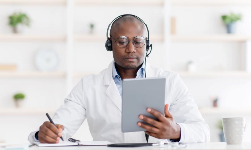 African American male physician listening to symposium on tablet computer