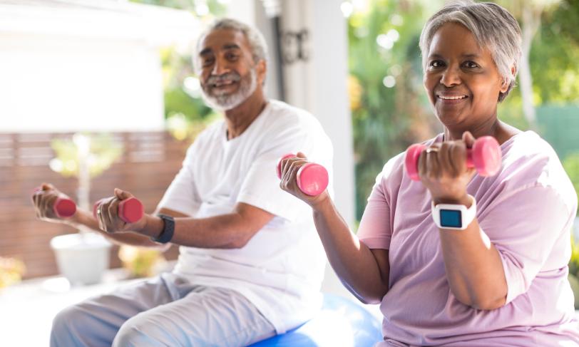 Smiling couple lifting dumbbells