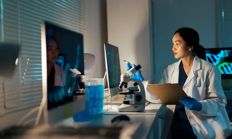 Female Asian medical researcher looking at desktop computer screen