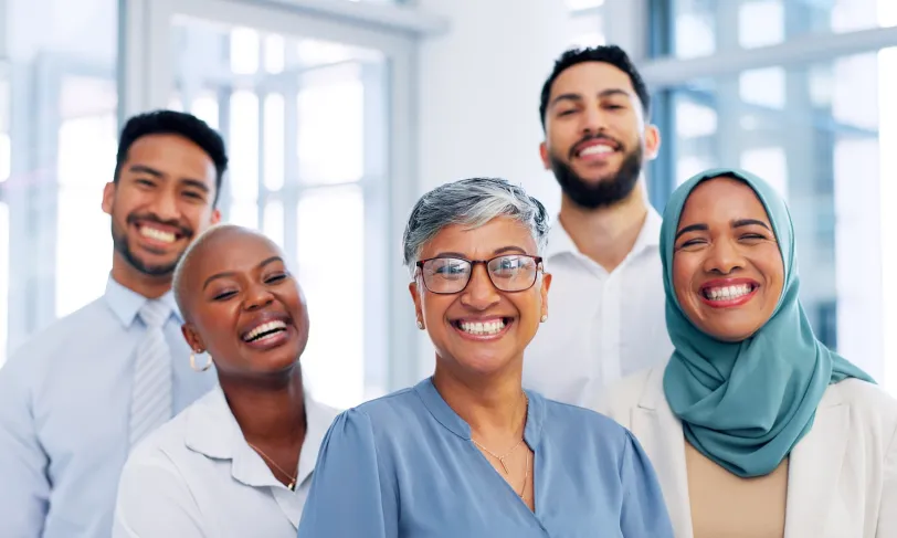 Diverse group of five smiling professionals looking at the camera.
