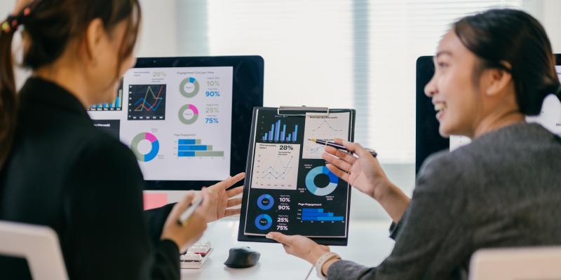 Two business women discussing graphs and charts