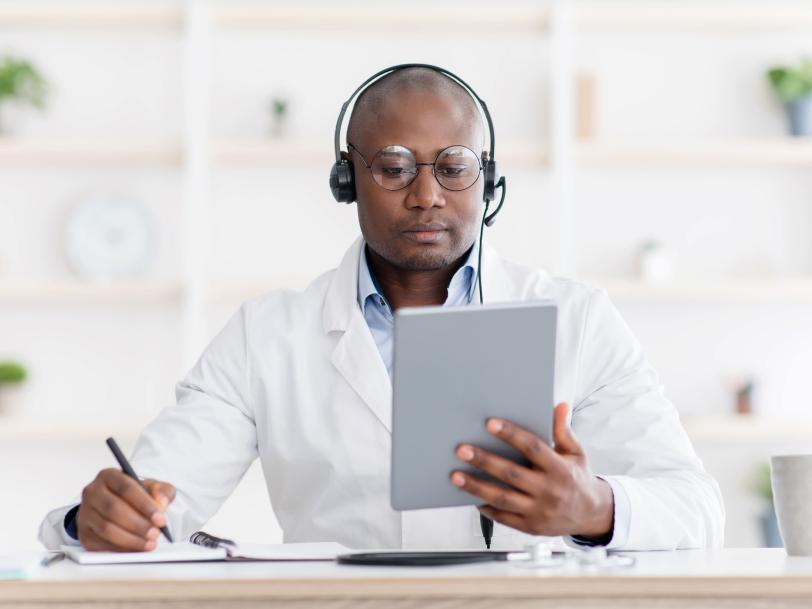 African American male physician listening to symposium on tablet computer