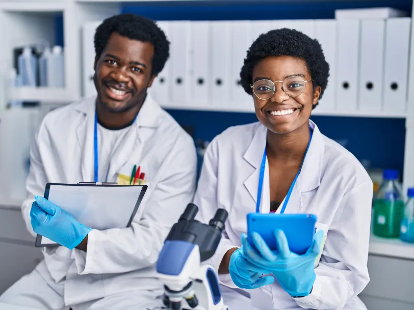 Two young African American scientists smiling in a laboratory setting.