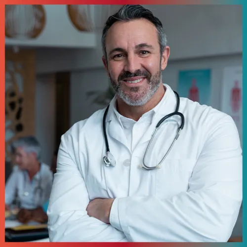 Smiling male doctor with beard and stethoscope around his neck