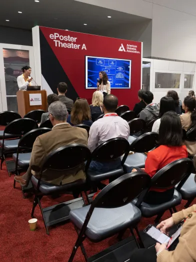 People seated in auditorium watching research presentation