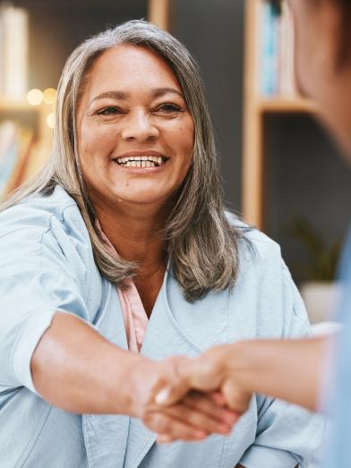 Smiling Latina shaking hands with woman