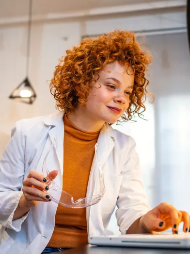 young woman working in a medical lab. Close up of scientist woman working in laboratory with laptop.